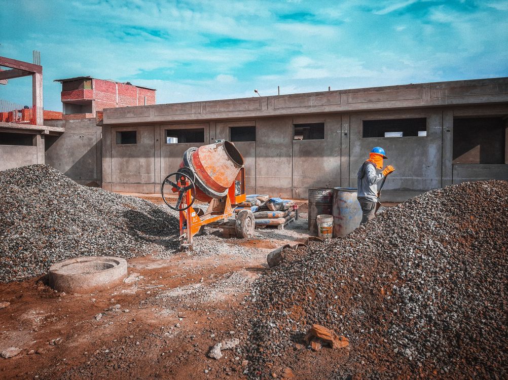 Cement mixer, materials, and a worker on a building site