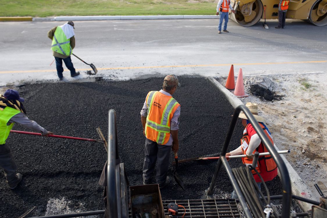 Road crews laying and working fresh asphalt
